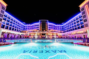 Un hôtel doté d’une grande piscine extérieure, de nombreux balcons et d’une structure centrale en verre.