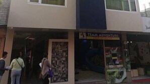 Un edificio de varios pisos con un diseño moderno, que presenta una tienda con el rótulo "TEAM ADVENTURE TOUR OPERATORS".