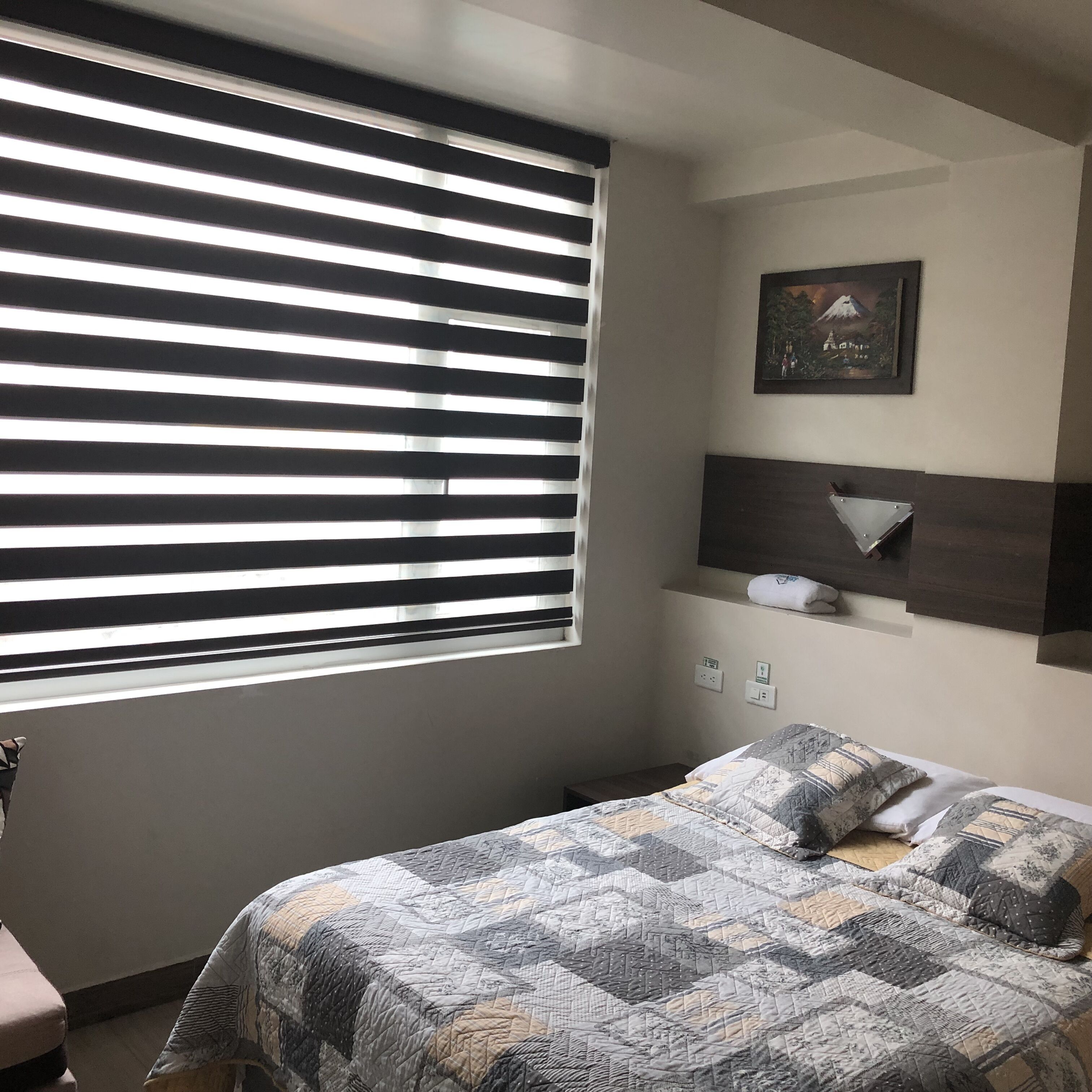 Una camera da letto con un letto, una finestra con tende, uno scaffale a parete e un quadro incorniciato.