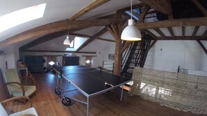 Un ampio loft con tavolo da ping pong, travi in legno e soffitto alto.