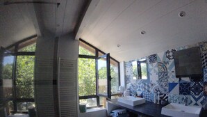 Un bagno moderno con due lavandini, piastrelle decorate e ampie finestre con vista sul verde.
