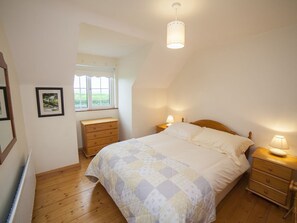 Une chambre à coucher avec un lit, une commode en bois, des tables de chevet et une fenêtre.
