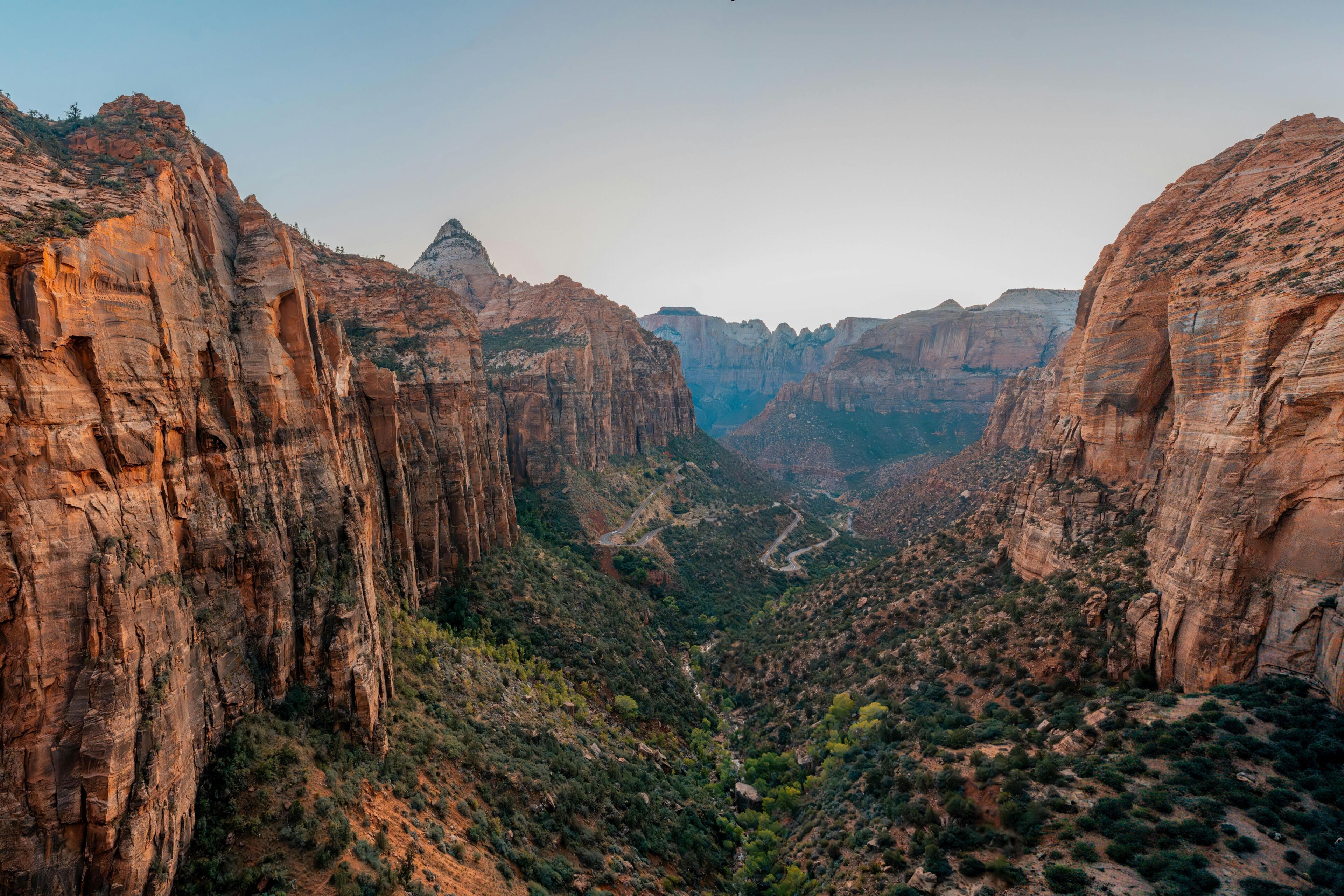 A canyon with steep rock walls and a winding road.