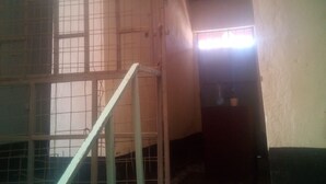 Una habitación con piso de baldosas, una escalera metálica y un ventanal con diseño de cuadrícula.