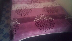 Una cama con una colcha y almohadas estampadas, una mesita de noche y una pared con un diseño geométrico de azulejos.