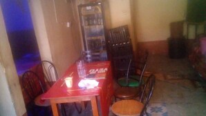 Un comedor con una mesa roja y cuatro sillas, un refrigerador y piso de baldosas.