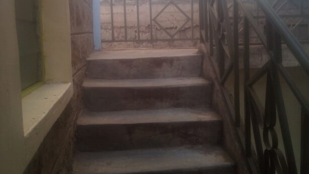 Una escalera con barandilla de metal que lleva a un balcón.