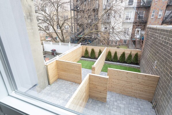 A view from a window of a courtyard with wooden planters and a brick wall.