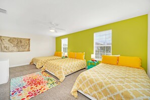 A bedroom with two beds, a colorful rug, and a map on the wall.