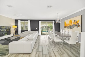 A modern living room with a sectional sofa, dining table with chairs, and a large abstract painting.