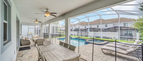 Un patio techado con piscina, mobiliario exterior y vista a edificios residenciales.