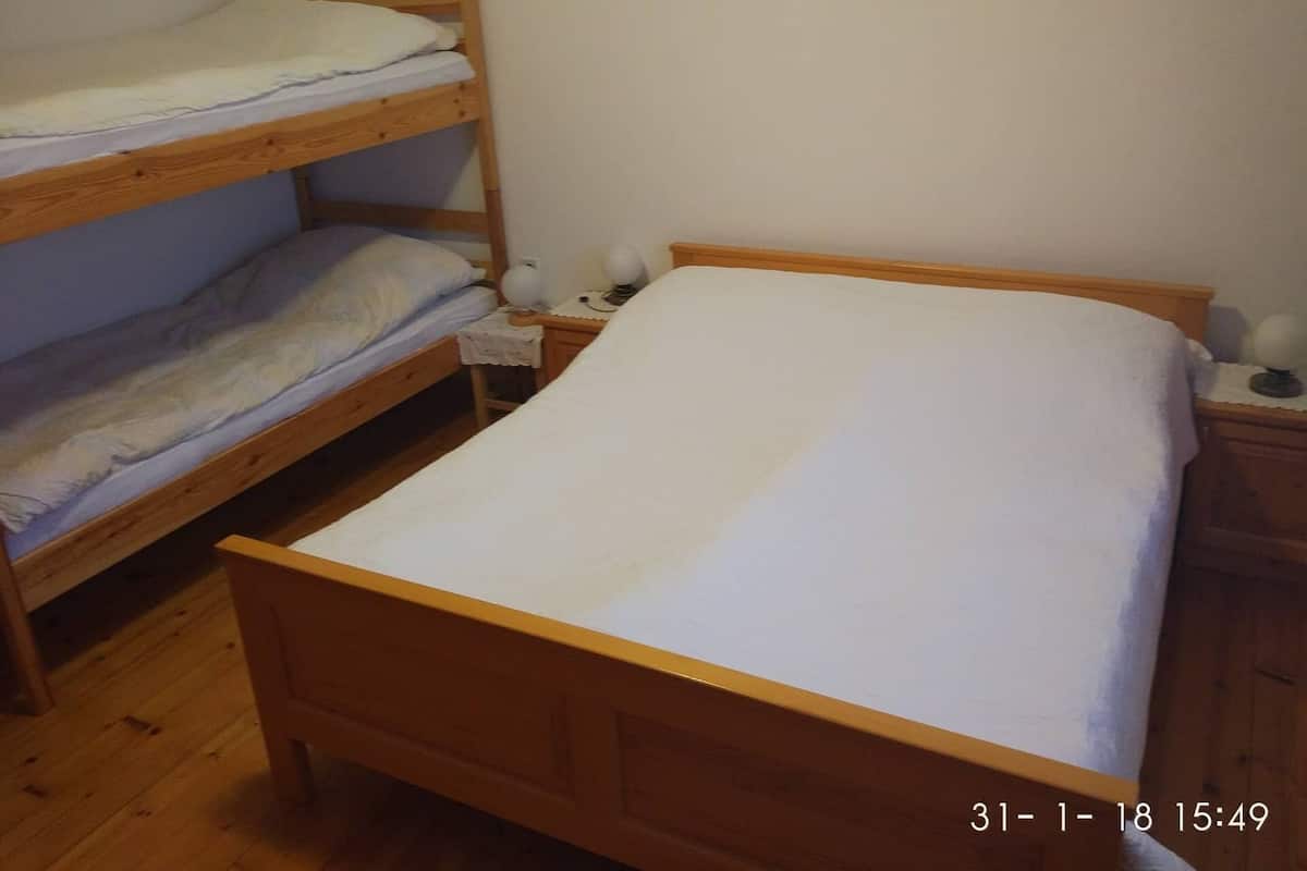 A single wooden bed with a white mattress in a room with wooden flooring.