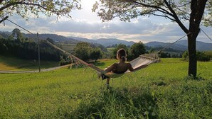 A hammock in a grassy field with a view of distant hills and a church.
