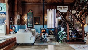 A cozy living room with a fireplace, a staircase, and a view of the outdoors.