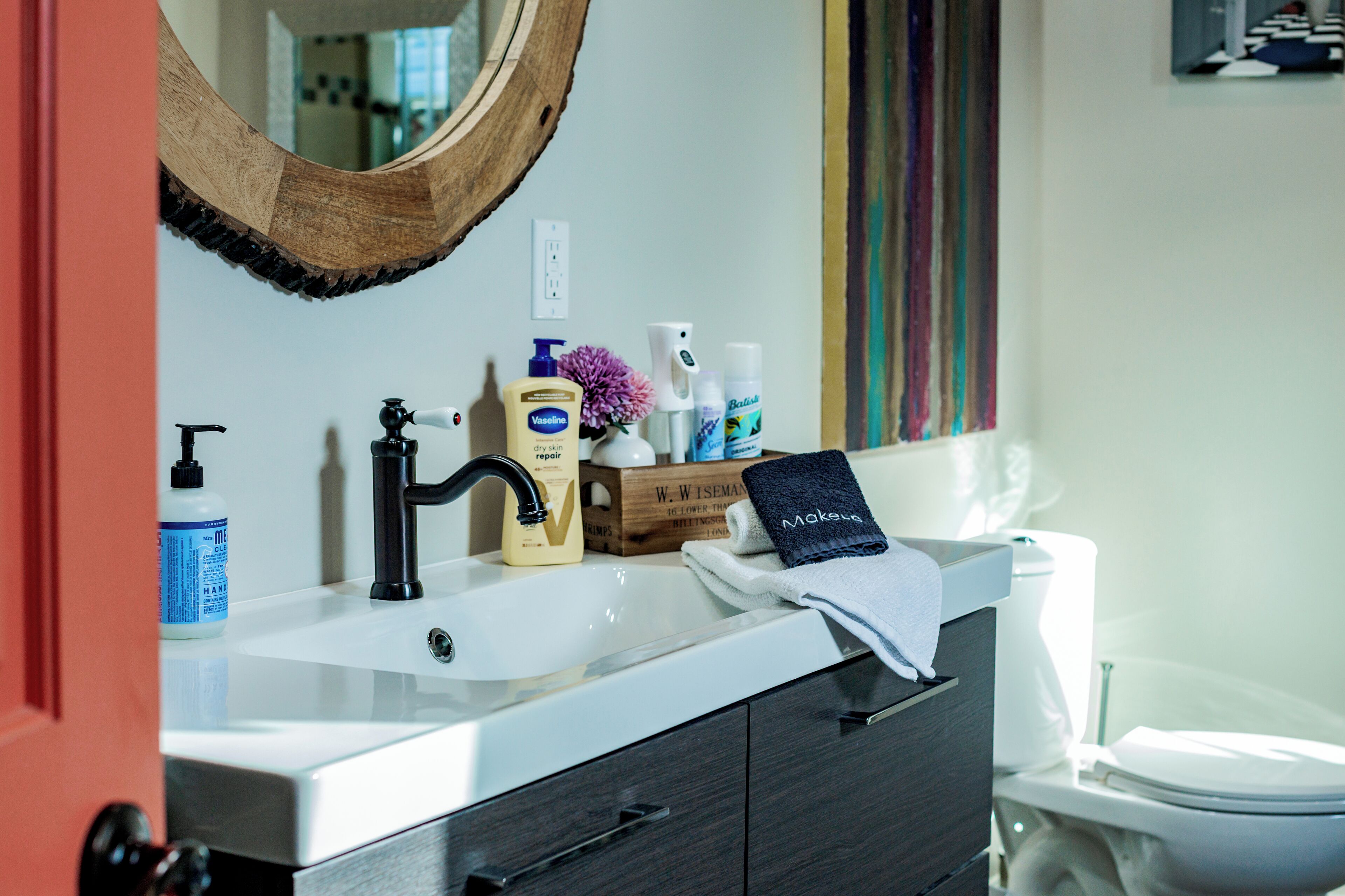 A bathroom with a white sink, dark wooden cabinet, and a toilet.