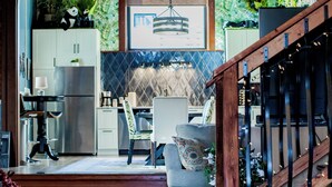 A spacious kitchen with a modern design, a dining area with a wooden staircase, and a view of the outdoors through a large arched window.