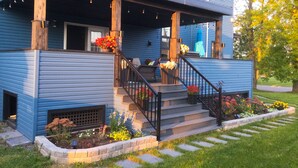 A blue house with a covered porch, steps, and a garden with flowers.