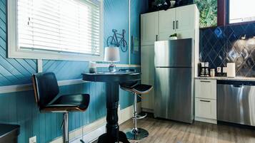 Una cocina con pared azul, un refrigerador, una estufa y una ventana con persianas.