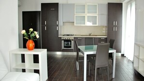 Una cocina moderna con armarios oscuros, una mesa de comedor blanca y un jarrón con flores.