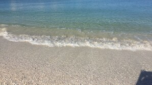 Una playa con agua cristalina y orilla pedregosa.