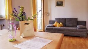 A living room with a grey sofa, a wooden coffee table, a vase with flowers, and a lamp.