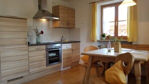 A compact kitchen with wooden cabinets, a built-in oven, and a dining area with a table and chairs.