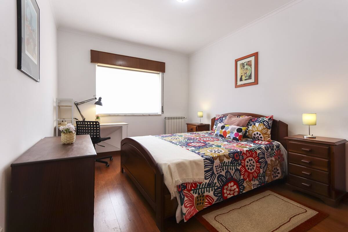 A bedroom with a bed, bedside tables, a desk, and a chair.