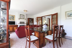 A dining area with a glass-top table, wooden chairs, and a red sofa.