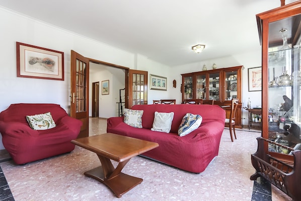 A living room with a red sofa, a wooden coffee table, and a glass cabinet with decorative items.