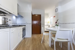 A kitchen with white cabinets, a stove, and a dining area with a table and chairs.
