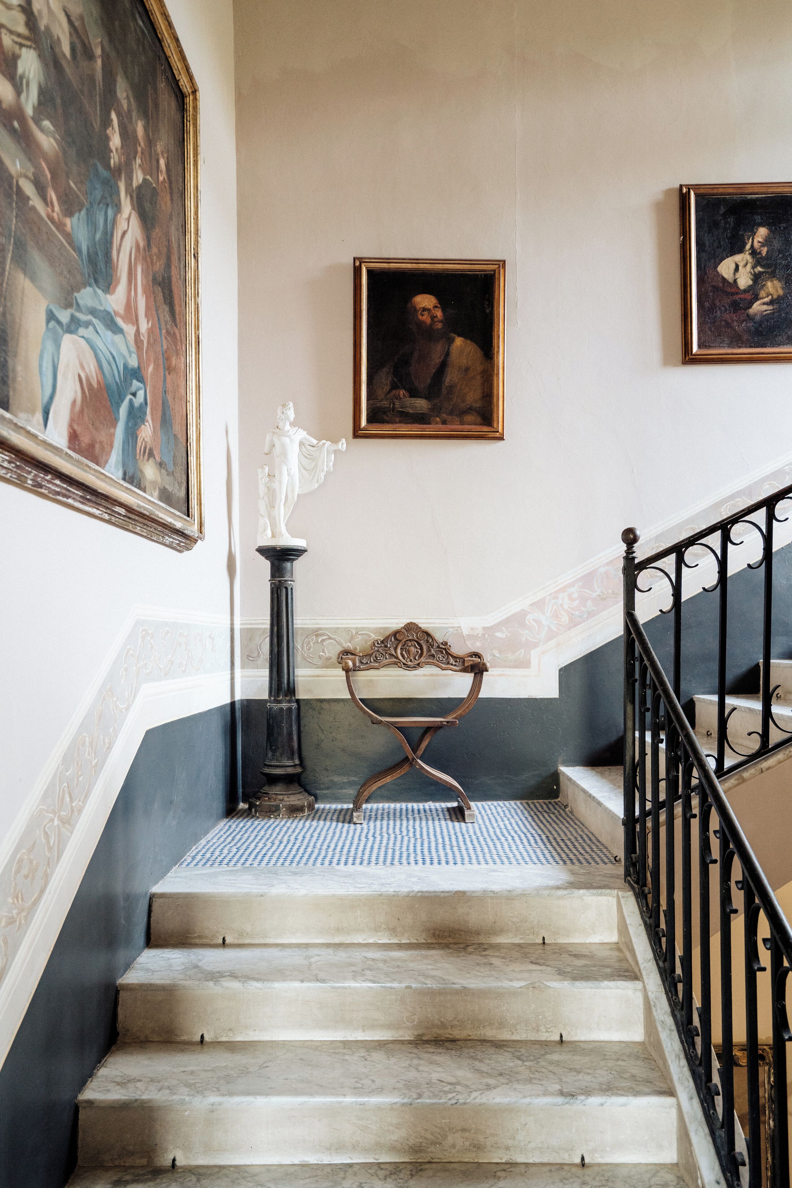 A staircase with marble steps, a black balustrade, and framed artwork on the walls.