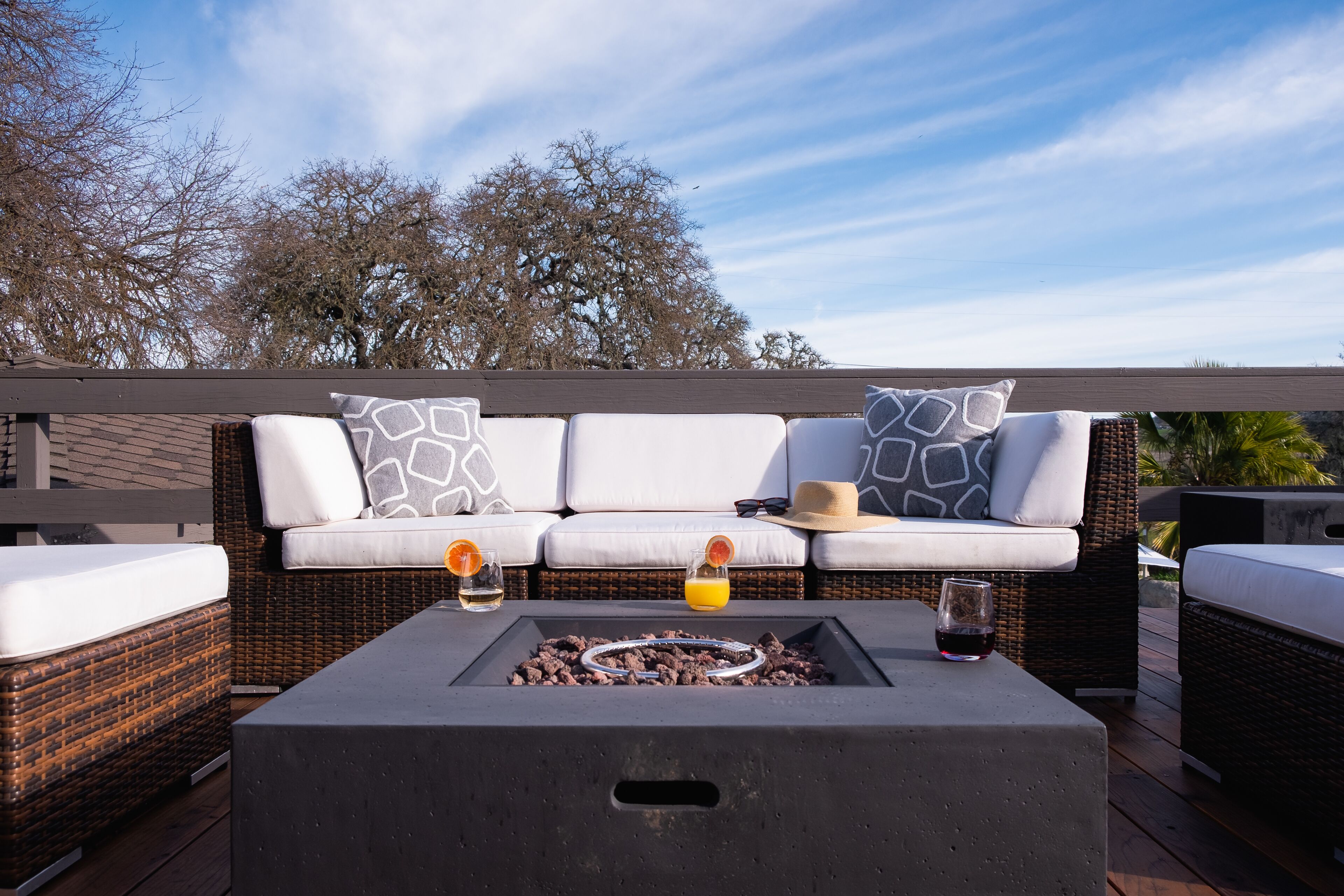 Une terrasse avec un ensemble de canapés, un foyer et deux verres de boissons.