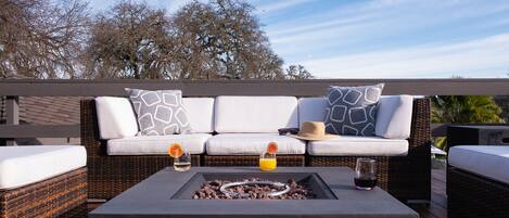Une terrasse avec un ensemble de canapés, un foyer et deux verres de boissons.