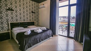 Habitación de hotel con cama, mesita de noche, ventana con cortinas y vistas al exterior.