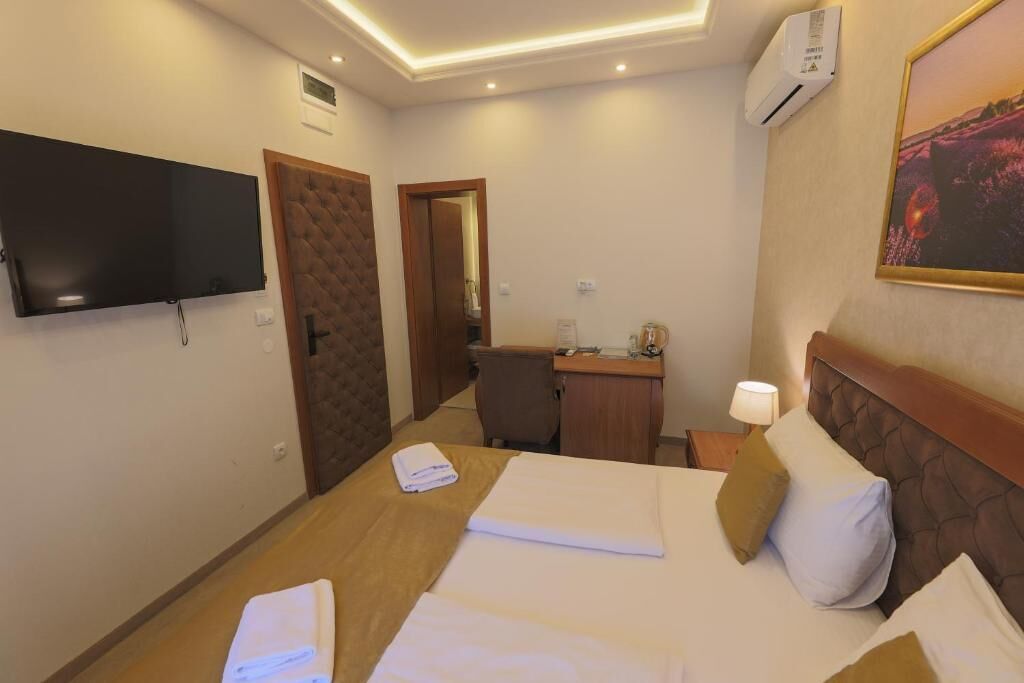 Une chambre d’hôtel équipée d’un lit, d’un bureau, d’une chaise, d’une télévision et d’un appareil de climatisation.
