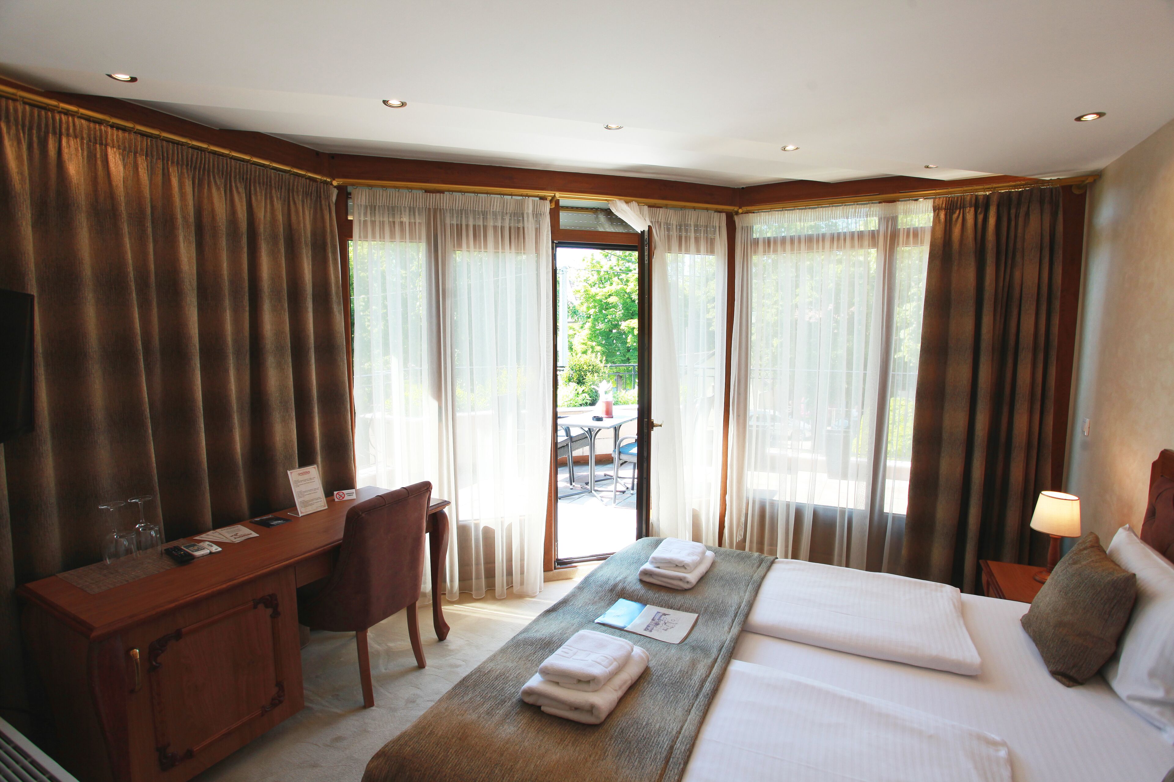 A hotel room with a bed, a desk, and a view of the outdoors.