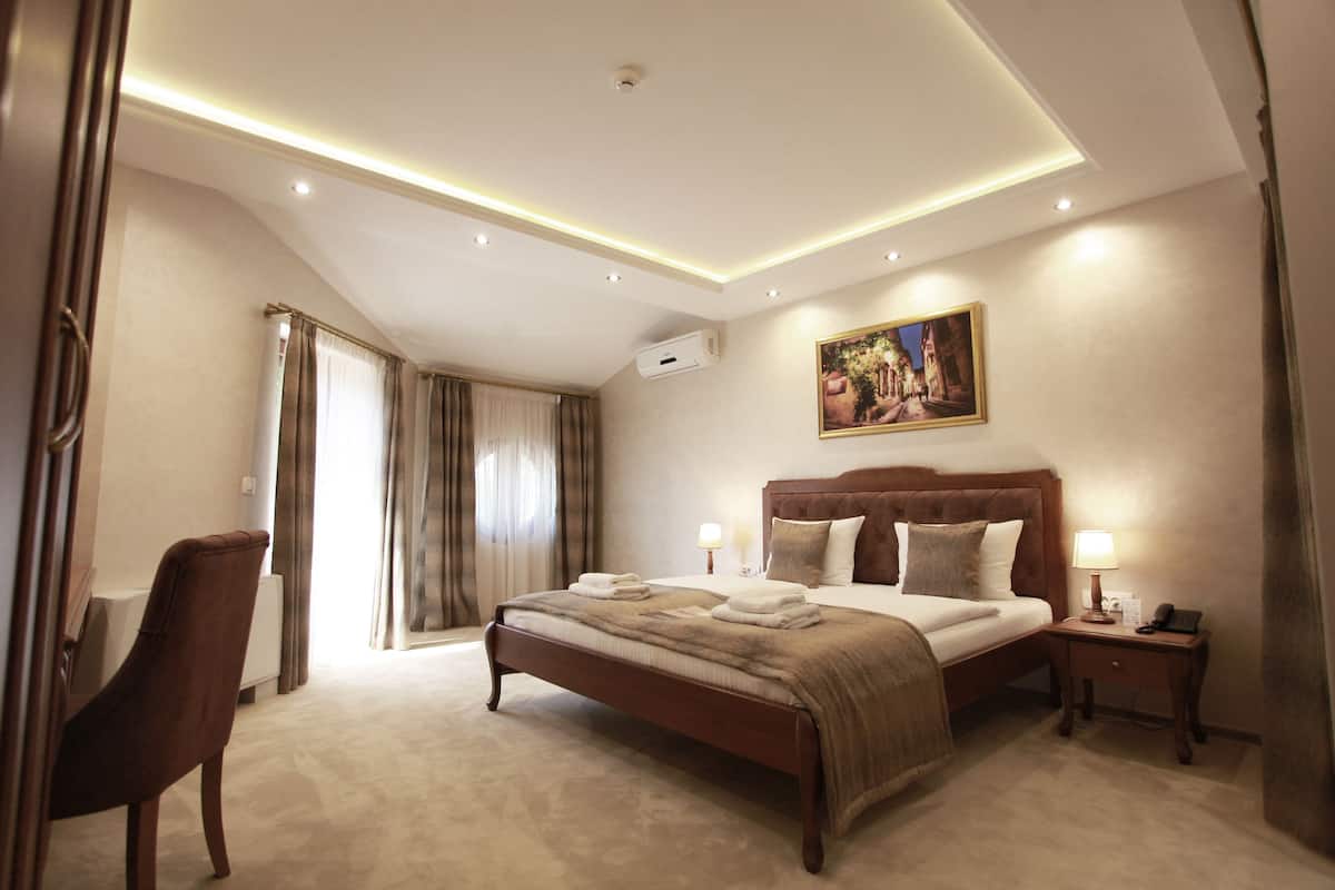 A hotel room with a large bed, bedside tables, a chair, and a painting on the wall.
