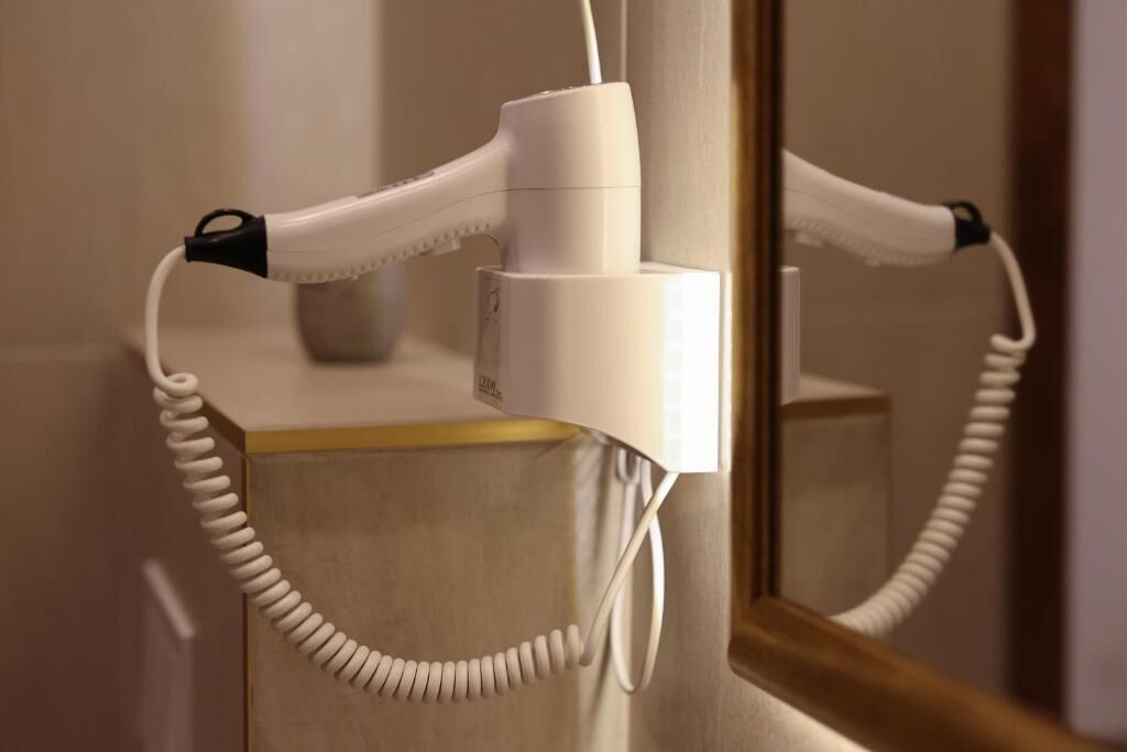 A hair dryer mounted on a wall with a cord.