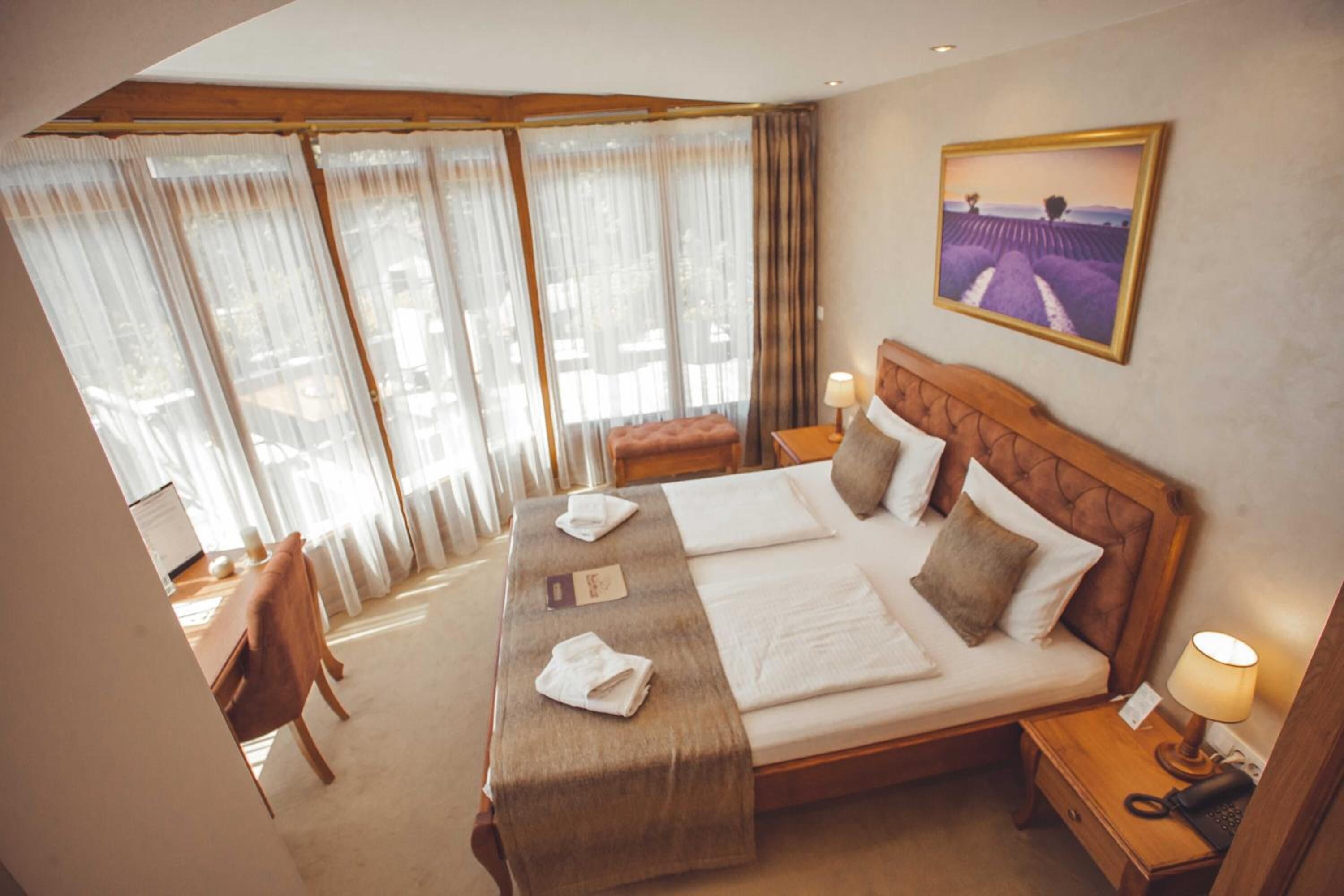 A hotel room with a large bed, two bedside tables, a desk, and a chair.