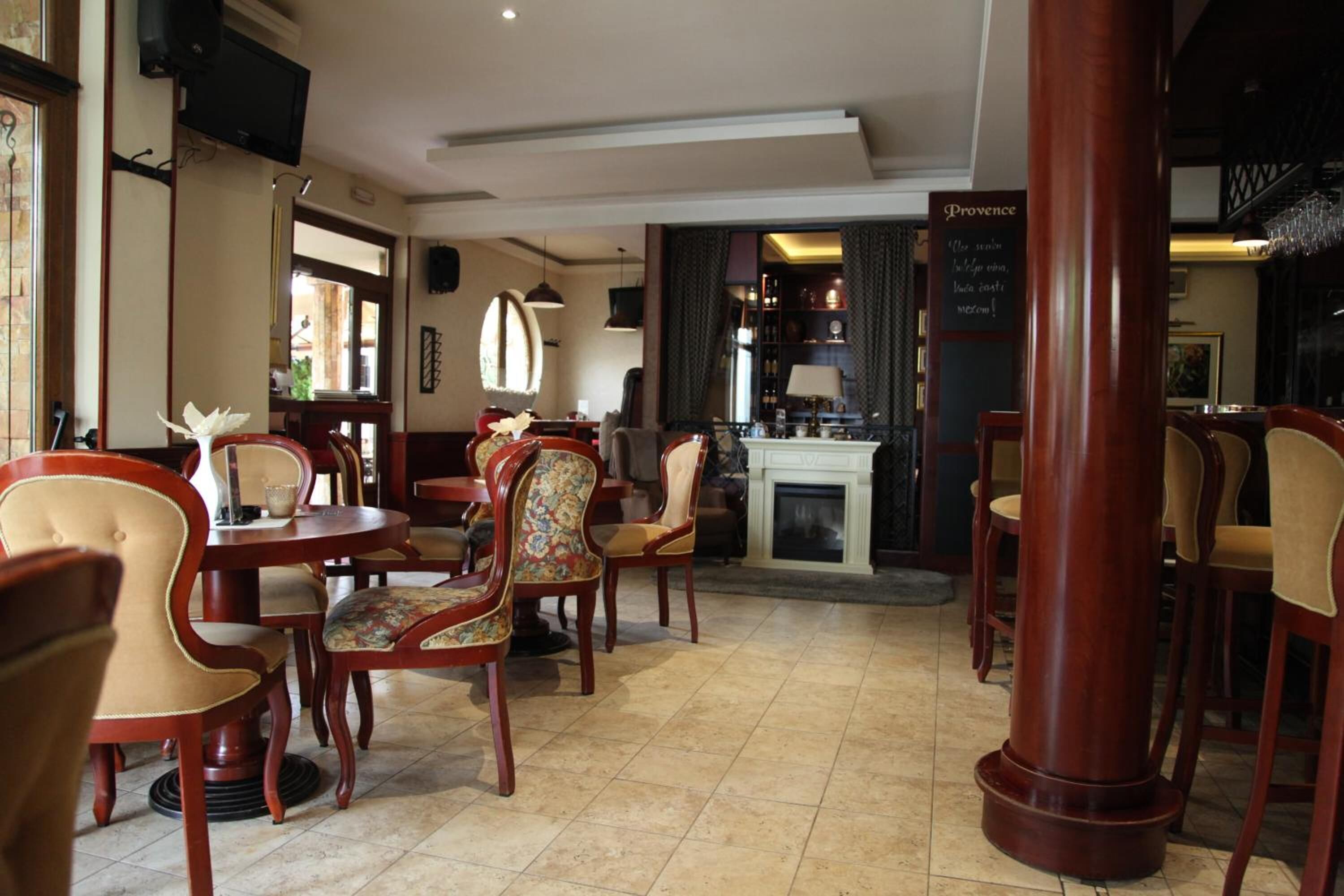 Un restaurante con mesas y sillas de madera, una chimenea y un letrero que dice "Provence".