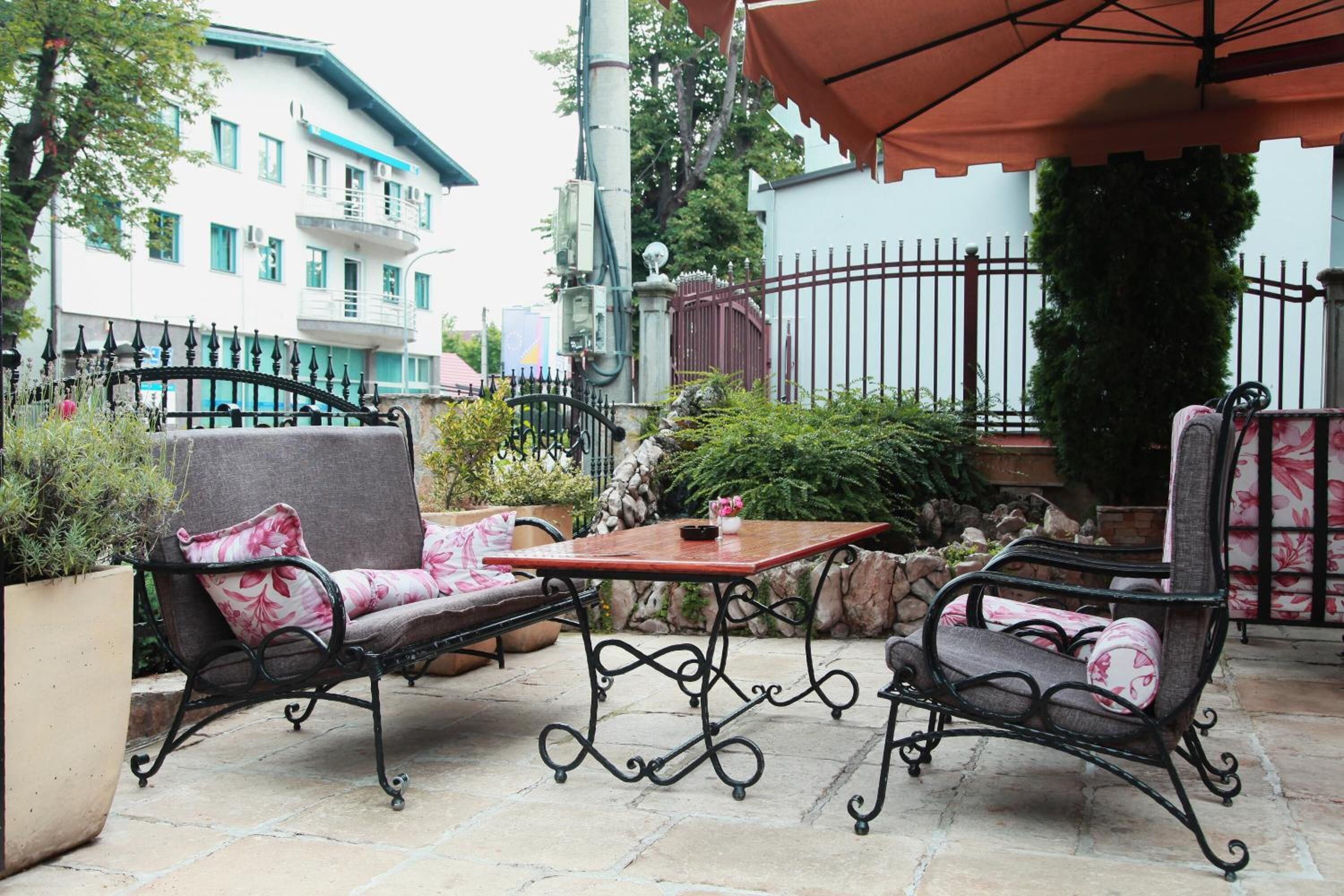 An outdoor patio with two cushioned chairs, a table, and an umbrella.