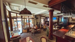 Een ruime hotellobby met een bar, zitgedeeltes en grote ramen met uitzicht op het omliggende landschap.