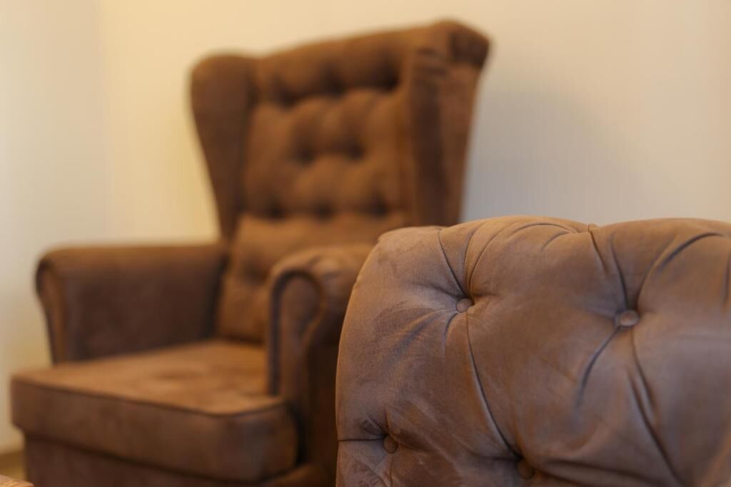 A brown tufted armchair with a high backrest.