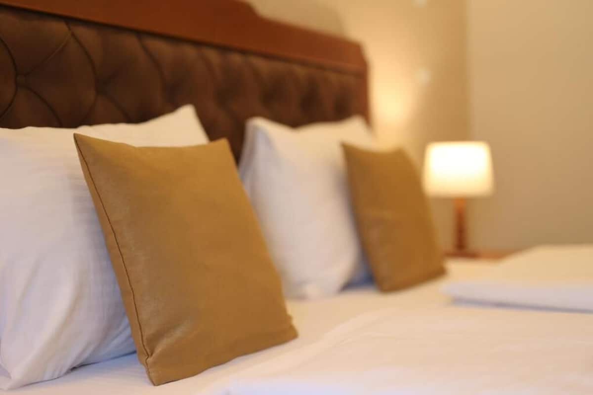 A neatly made bed with white and brown pillows and a wooden headboard.