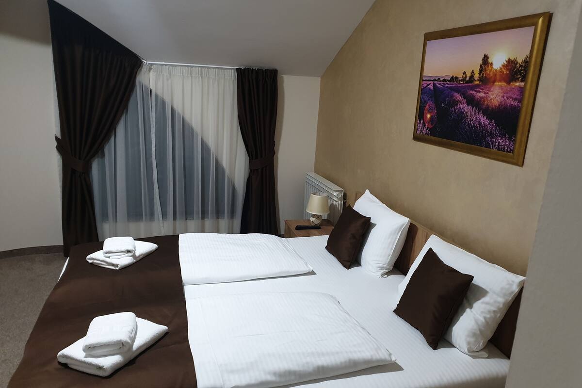 A hotel room with a large bed, a nightstand, a lamp, and a painting on the wall.