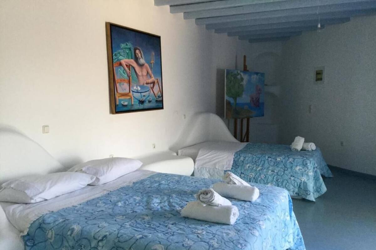 A hotel room with two beds, a painting on the wall, and a small table with towels.