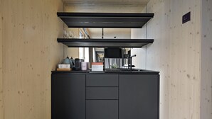 Eine moderne Küche mit schwarzen Schränken, einer Edelstahl-Dunstabzugshaube und einer Arbeitsplatte mit Kaffeemaschine und Weingläsern.