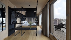 Ein modernes Interieur mit einem Etagenbett, einem kleinen Tisch mit einer Vase und Blick auf einen Balkon mit einem Stuhl.