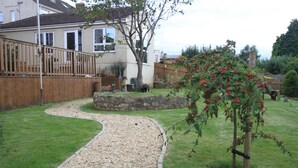 Un jardin résidentiel avec un chemin de gravier, une clôture en bois et une maison en arrière-plan.