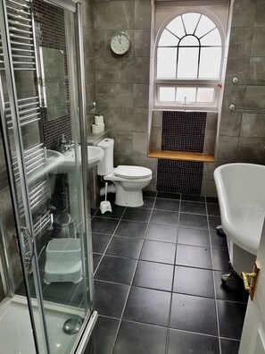 Une salle de bain moderne avec une douche à l’italienne, des toilettes, un lavabo et une baignoire.